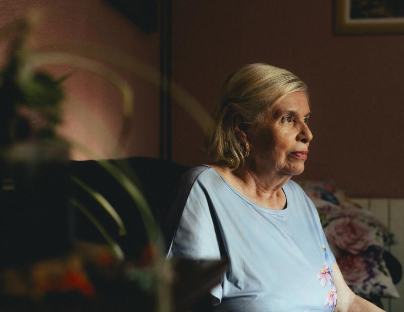 Una mujer mayor sentada sola en su casa.